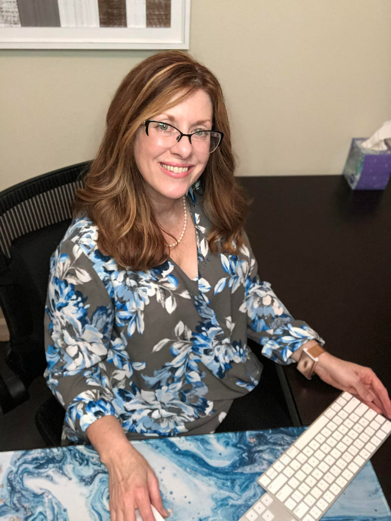 Smiling woman working at desk wearing the rose gold Embr Wave bracelet.