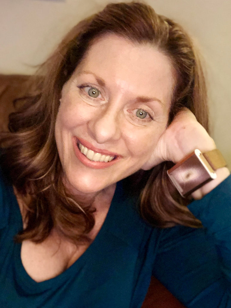 Smiling woman wearing the rose gold Embr Wave bracelet.