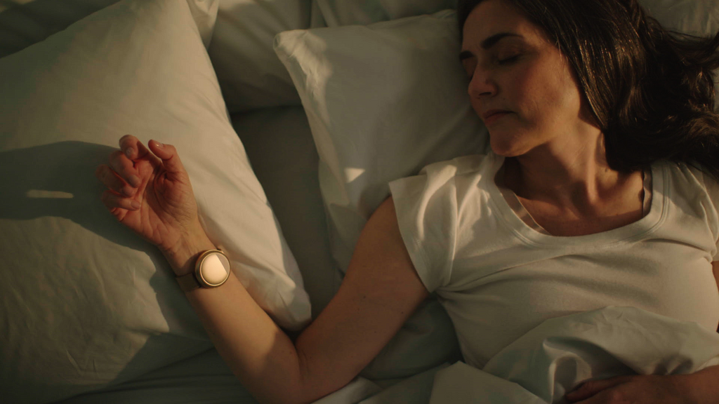 Woman wearing the rose gold Embr Wave 2 on her right wrist while she sleeps.