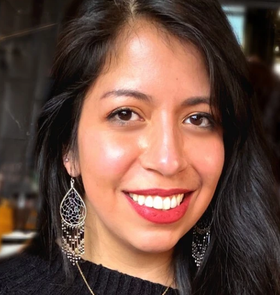 Headshot of smiling woman with large dream-catcher earrings.