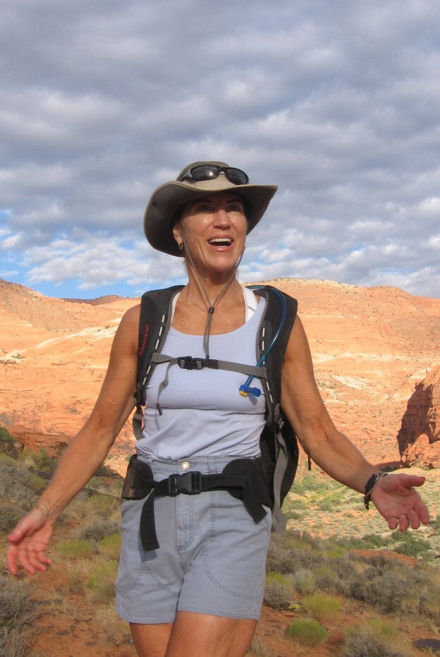 Dr. Pam Peeke hiking in a sunny desert wearing a bucket hat, backpack and the black Embr Wave.