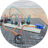Breadboard circuit with speaker on grey engineering mat