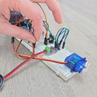 Hand working on breadboard circuit with servo