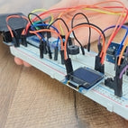 Hands holding breadboard circuit with various electronic components