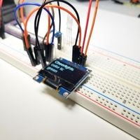 Breadboard circuit with OLED screen displaying Cheerlights message