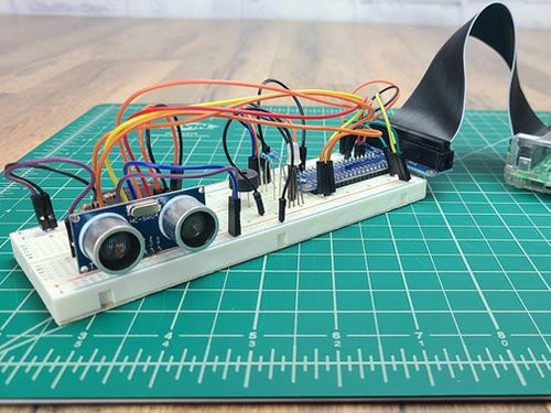 Breadboard circuit with ultrasonic sensor sitting on green engineering mat