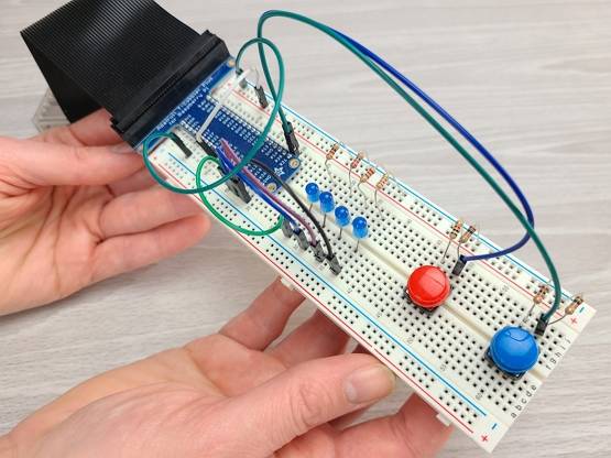 Hands holding a Raspberry Pi Breadboard Circuit including switches, resistors, jumper wires, LEDs, and a GPIO header.