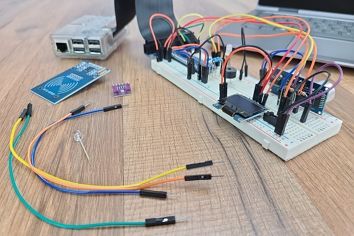 Raspberry Pi Breadboard Circuit with Electronic Components and Laptop Sitting on Wood Table