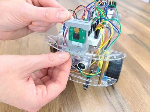 Hands adjusting robot on wood table