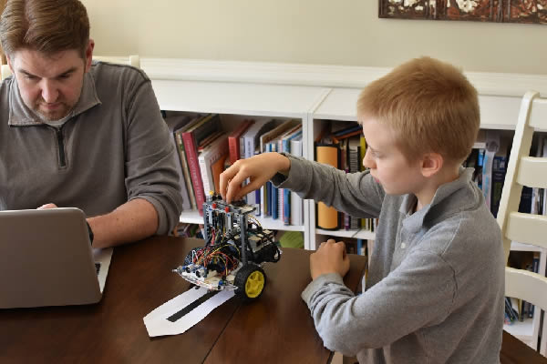 Man and boy building line following robot using Python code