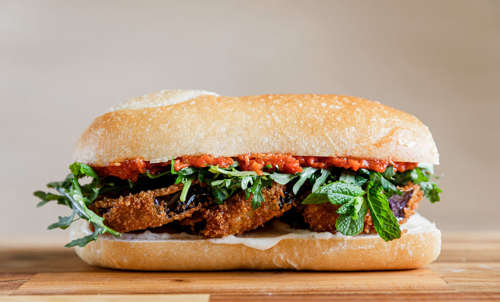 Pei Pei Chei Ow's eggplant and tomato jam sandwich on a wooden countertop against a beige wall