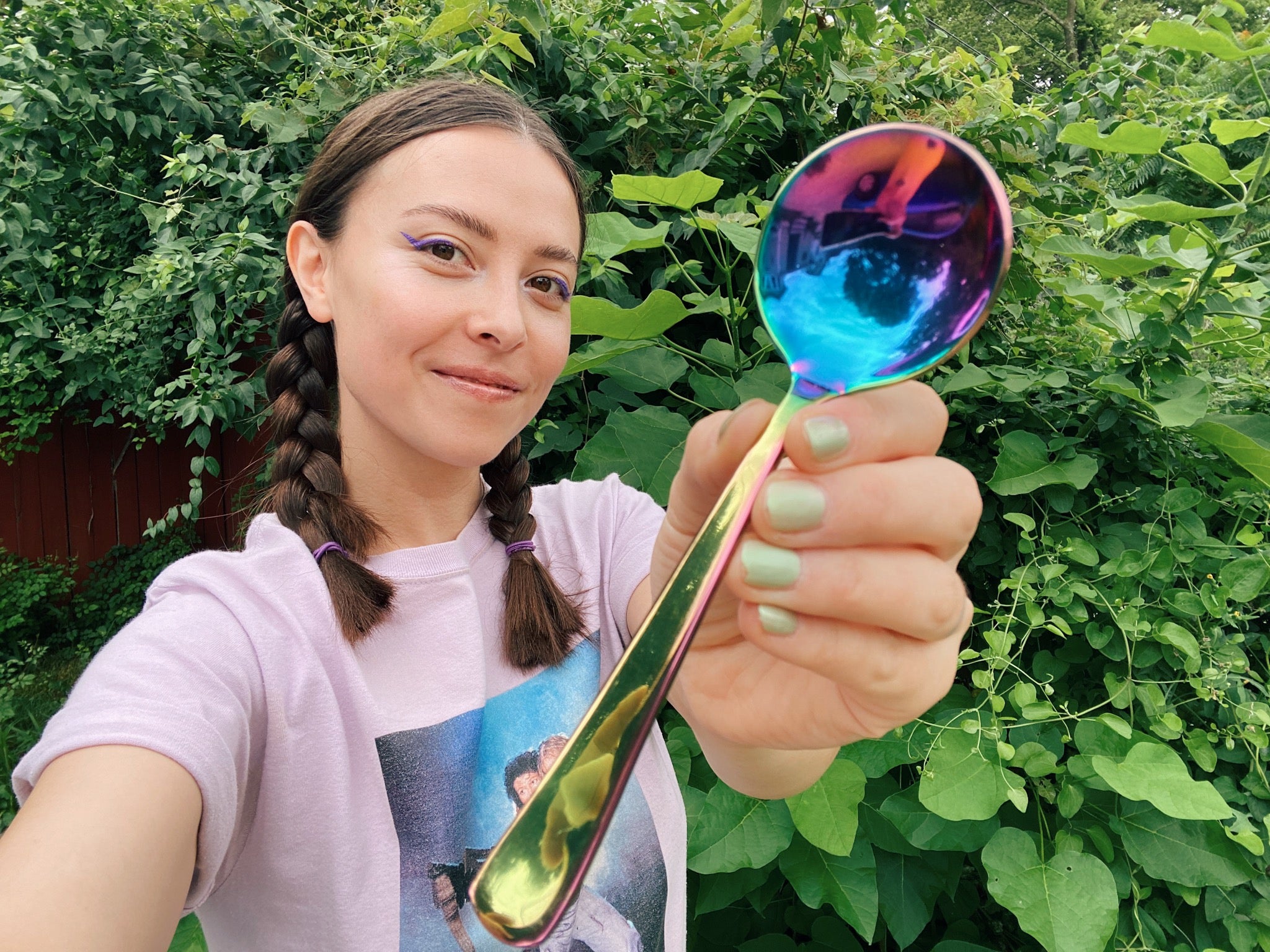 Umeko Motoyoshi holding an Umeshiso rainbow cupping spoon with lush greenery in the background
