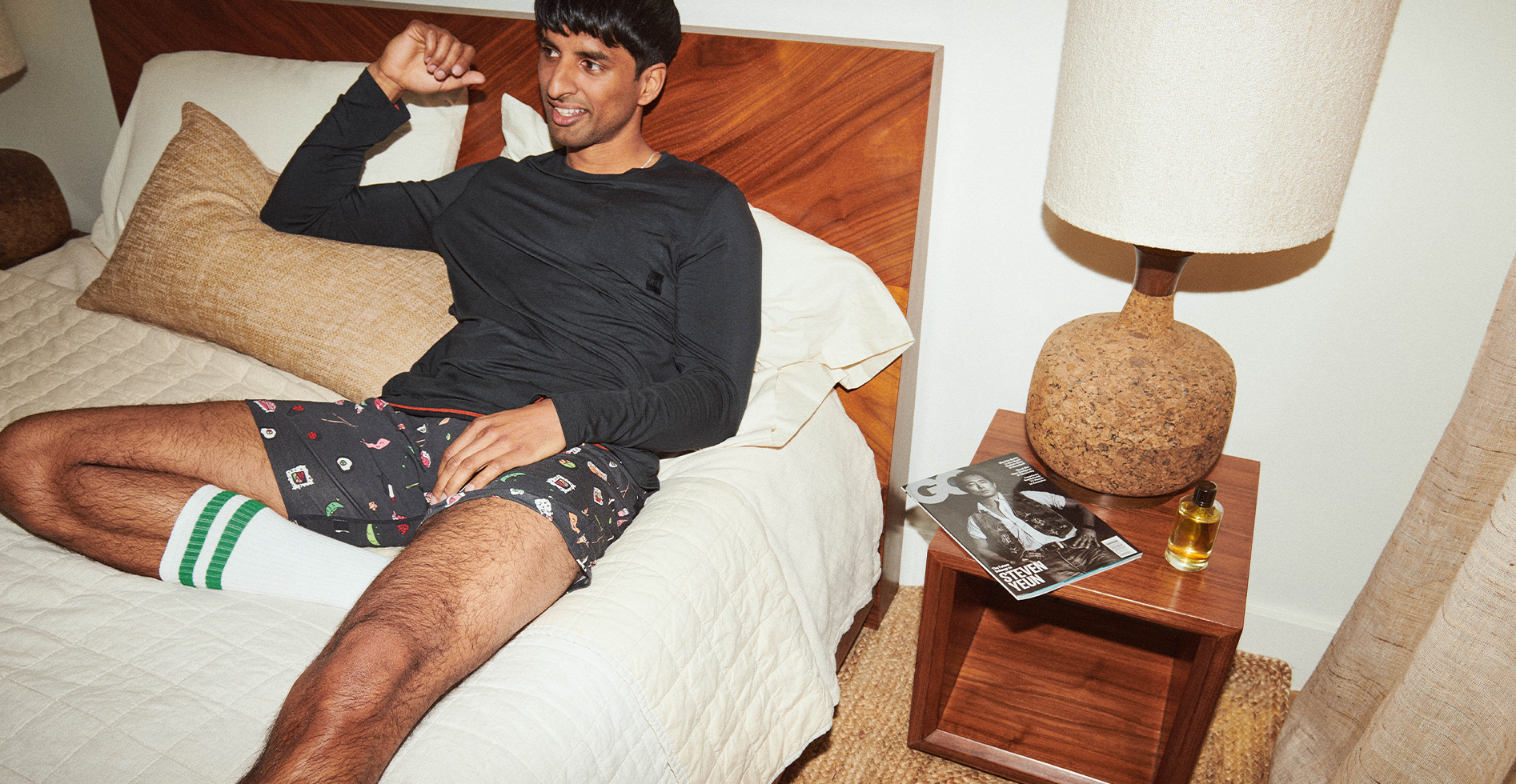 Man in comfortable shorts and shirt propped up in bed