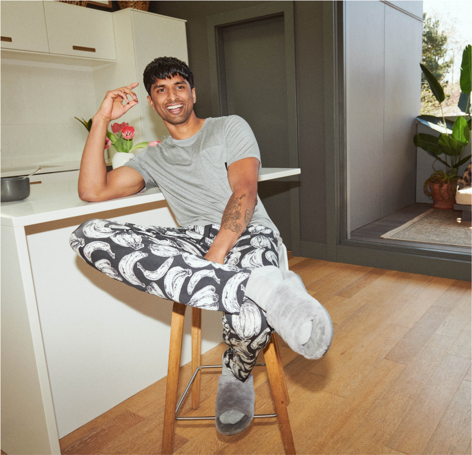 A person sitting in a kitchen in the Sleepwalker Short Sleeve Crew and Sleepwalker Sleep Pant in Banana Bunch- Black