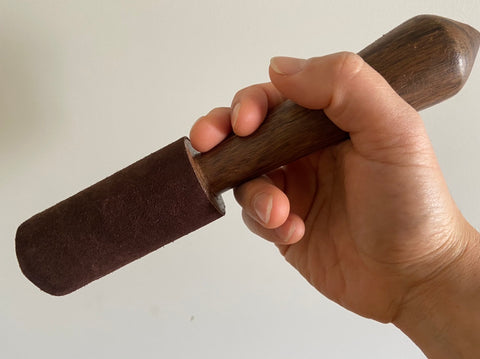 Close up of singing bowl mallet gripped in hand