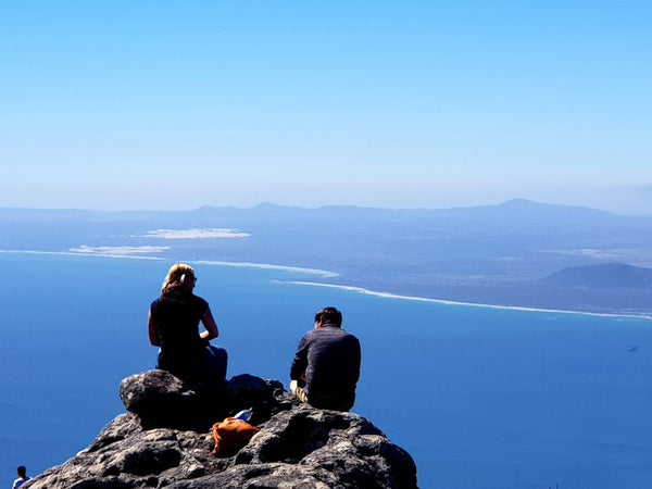 A Couple Sitting On Table Mountain Looking Across The Bay To Bloubergstrand | Cape Town | Western Cape | South Africa | Australian Cricket Tours