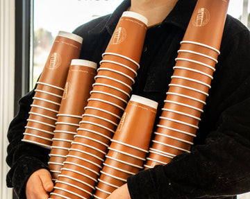 someone holding stacked customized coffee cups. Trendy and fun customized coffee cup. Hot cup factory has every product you need for your cafe, work with a professional designer for FREE to customize your coffee shop with hot cup factory today! 