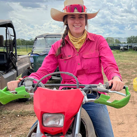 Ruby souriant sur une moto hors route dans sa ferme