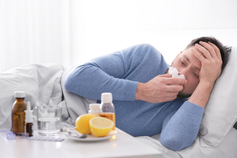 Man sick in bed with medicine next to him