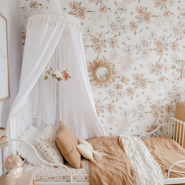 White canopy draped over white metal bed in girls bedroom