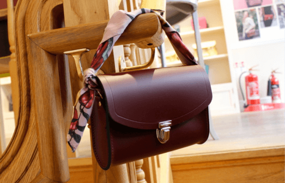 Leather handbag with scarf wrapped around the handle, hanging of the banisters of some stairs 