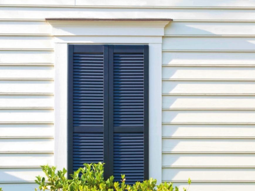cream house with navy louvered shutters