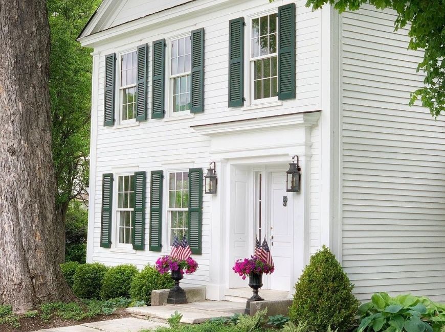white house with dark green shutters and planters in the front 