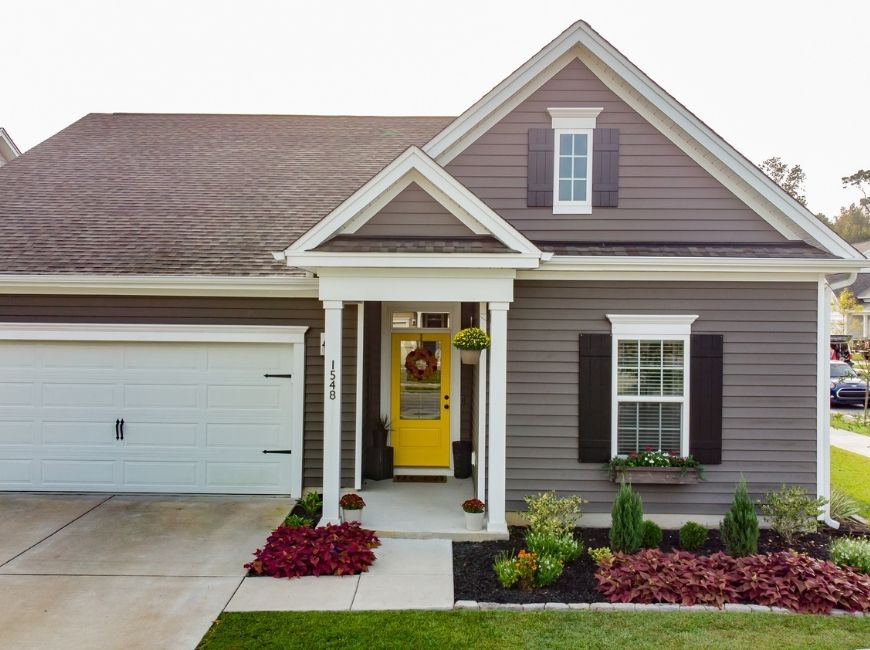 grey home with black shutters and yellow door