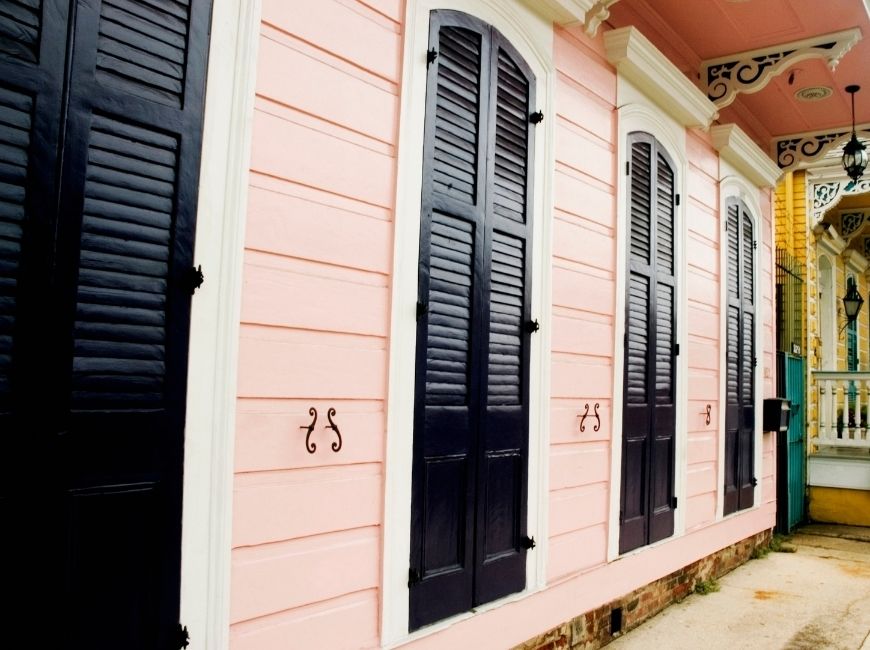 pink home with black closed shutters