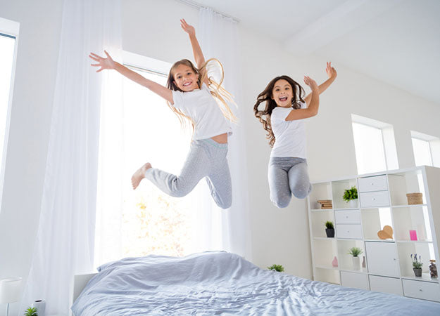 cheerful kids jumping on bed