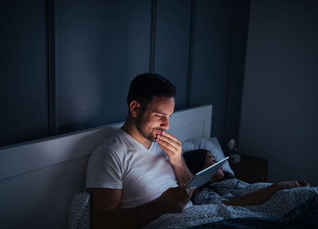 man looking at tablet in bed