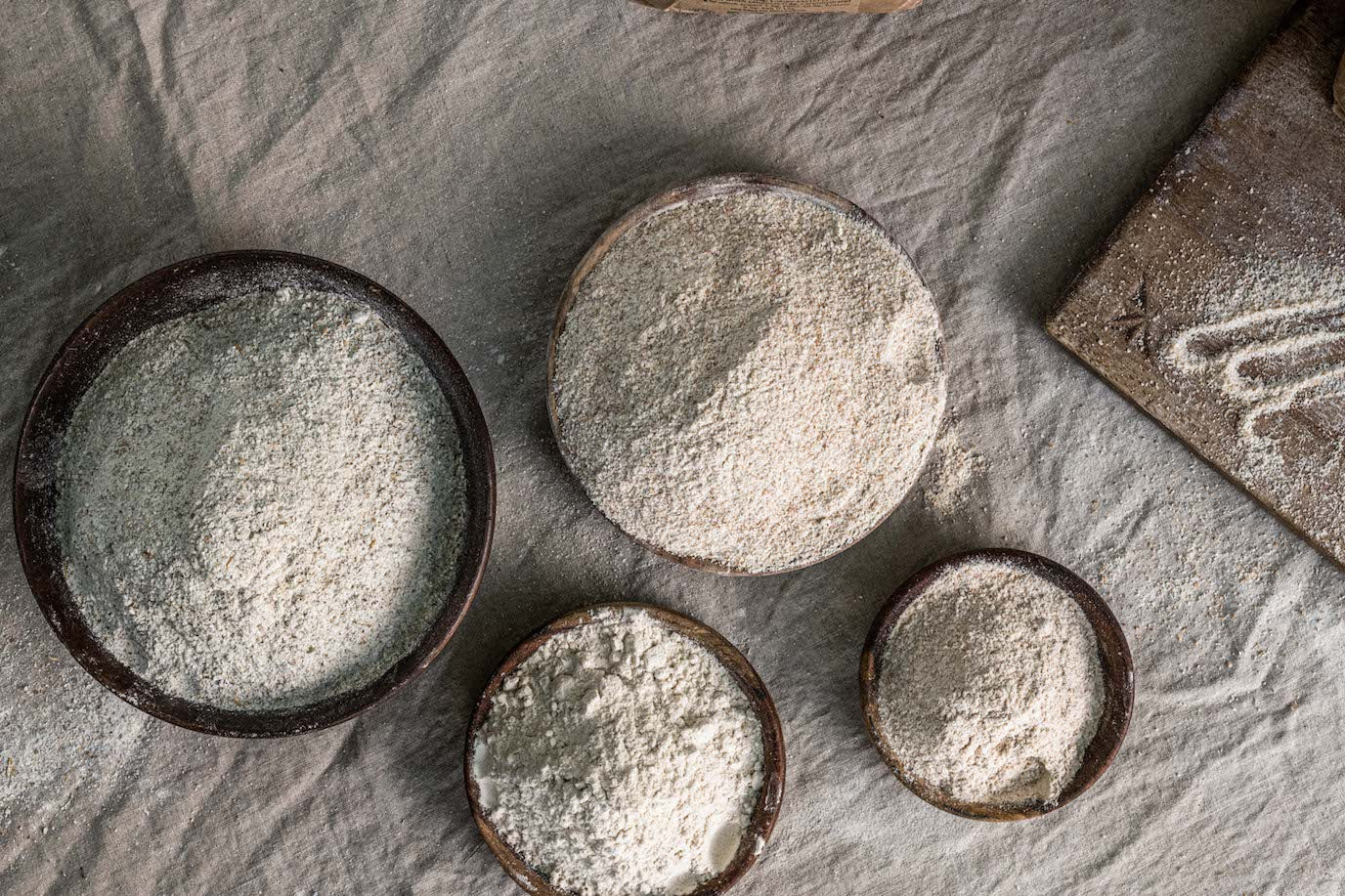 Flour in bowls on a white linen background 