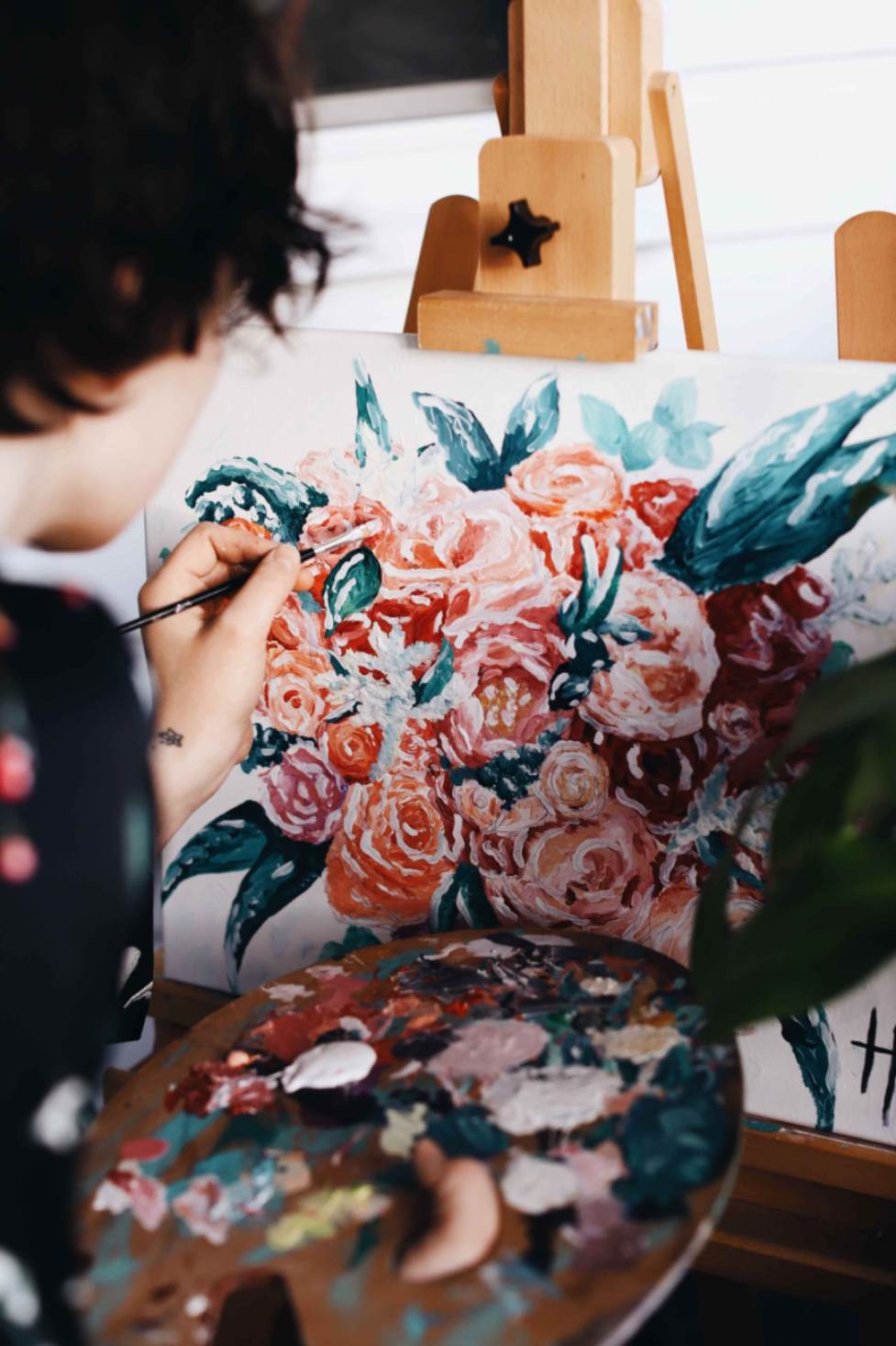 A person painting flowers on a canvas