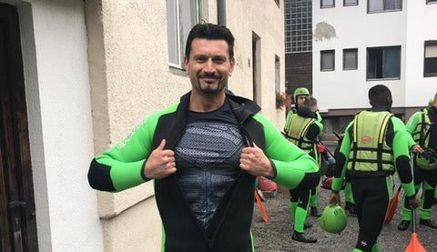 Echelon Instructor Özhan Gürel posing in a green and black wetsuit and a black superman shirt