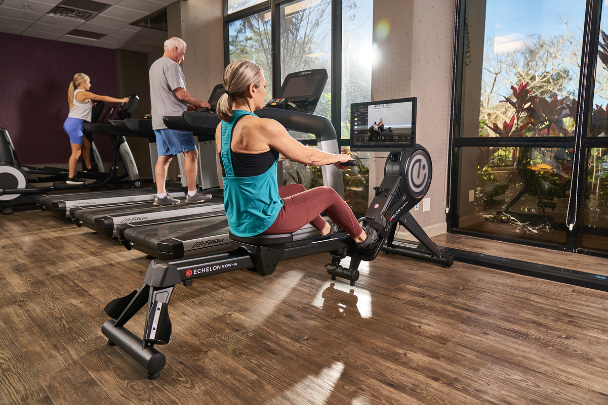 A woman is riding a rowing machine in a gym