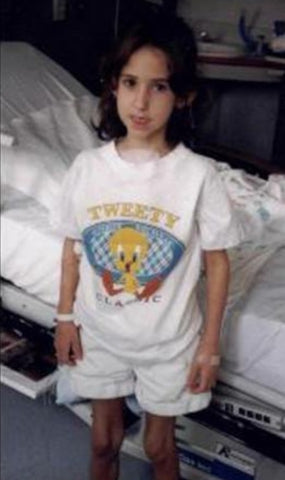 Echelon Member Melissa S. as a child stands next to her hospital bed after her first transplant.