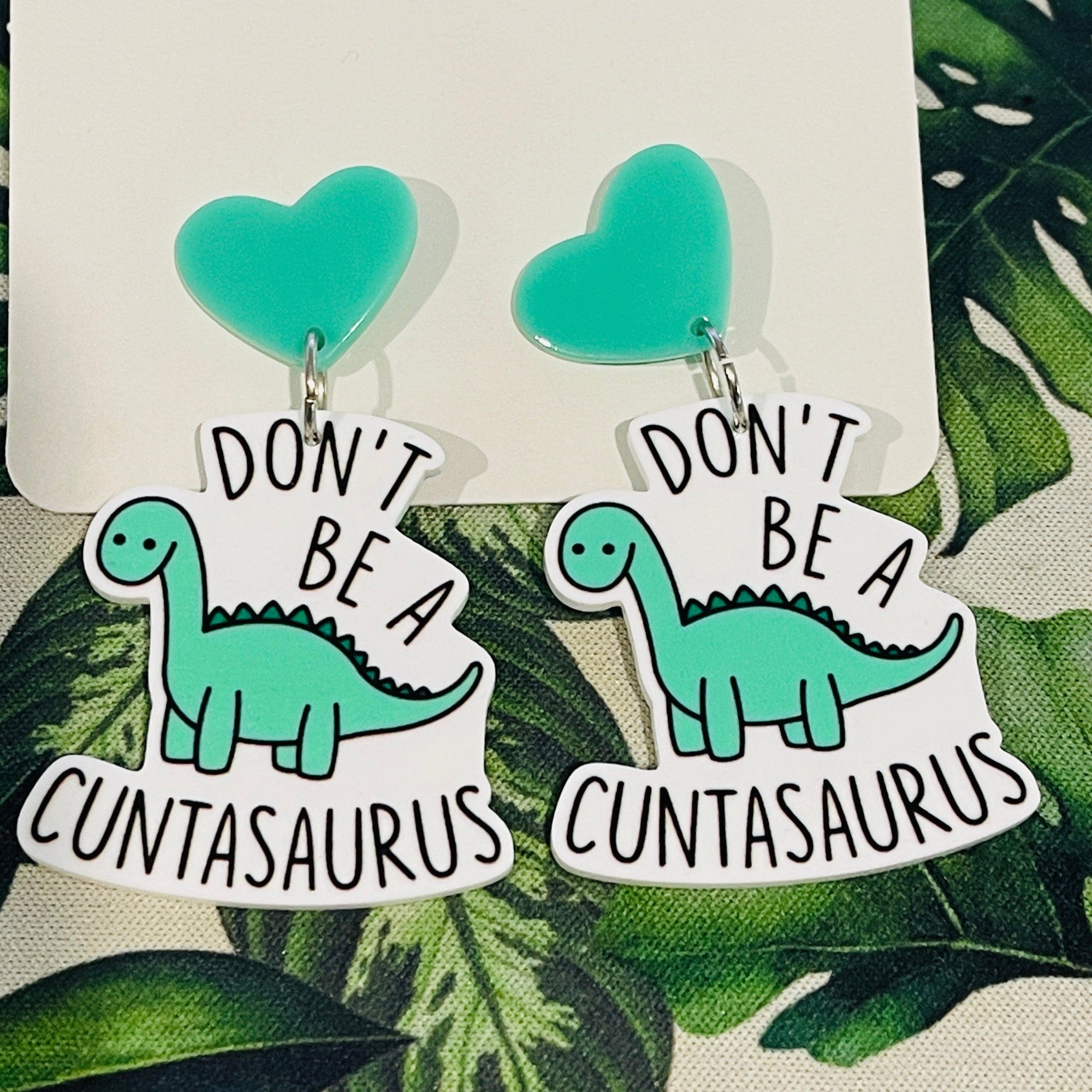 https://cdn.shopify.com/s/files/1/2423/8037/products/tigc-the-inappropriate-gift-co-don-t-be-a-cuntasaurus-earrings-30508071223338_2000x.jpg?v=1678776523