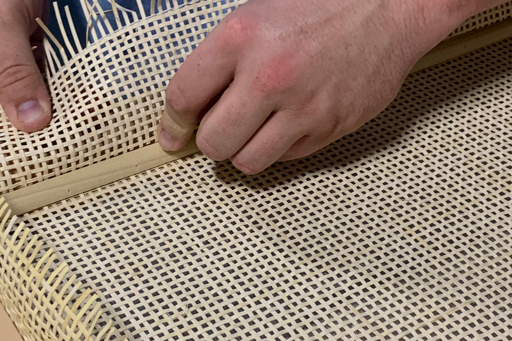Excess cane being trimmed from moulding