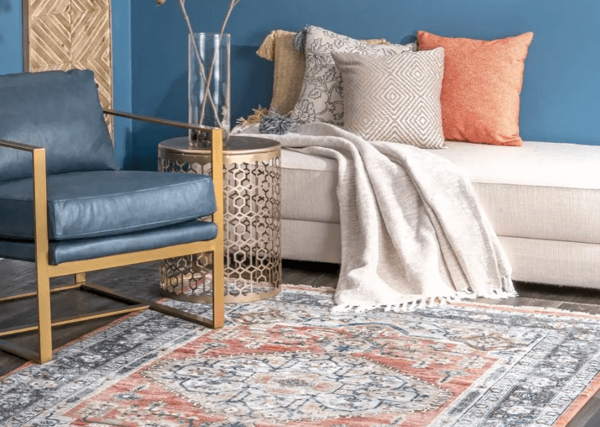 A colorful area rug with matching pillows and chair from Insider.com