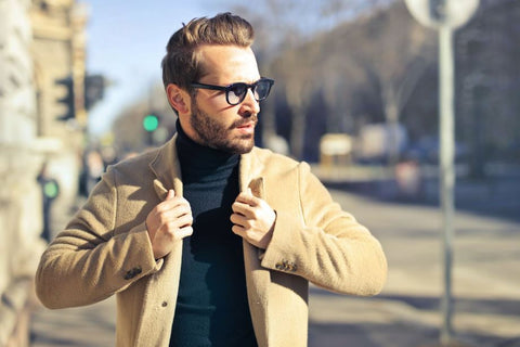 bearded man in tan jacket with glasses