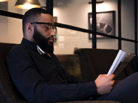 man with curly beard and glasses reading
