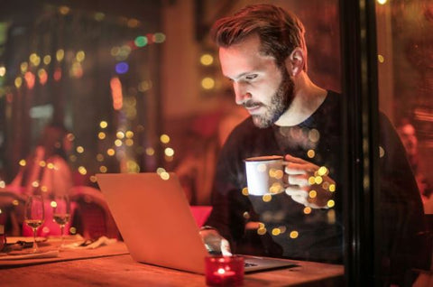 bearded man at coffee shop working on a laptop