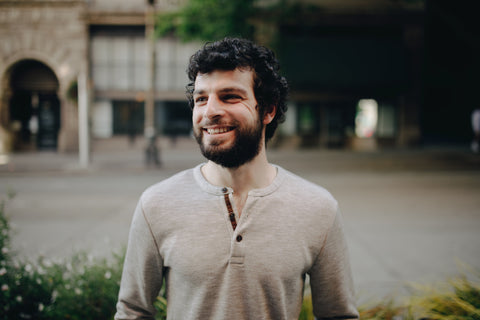 man with curly hair and beard in taupe shirt