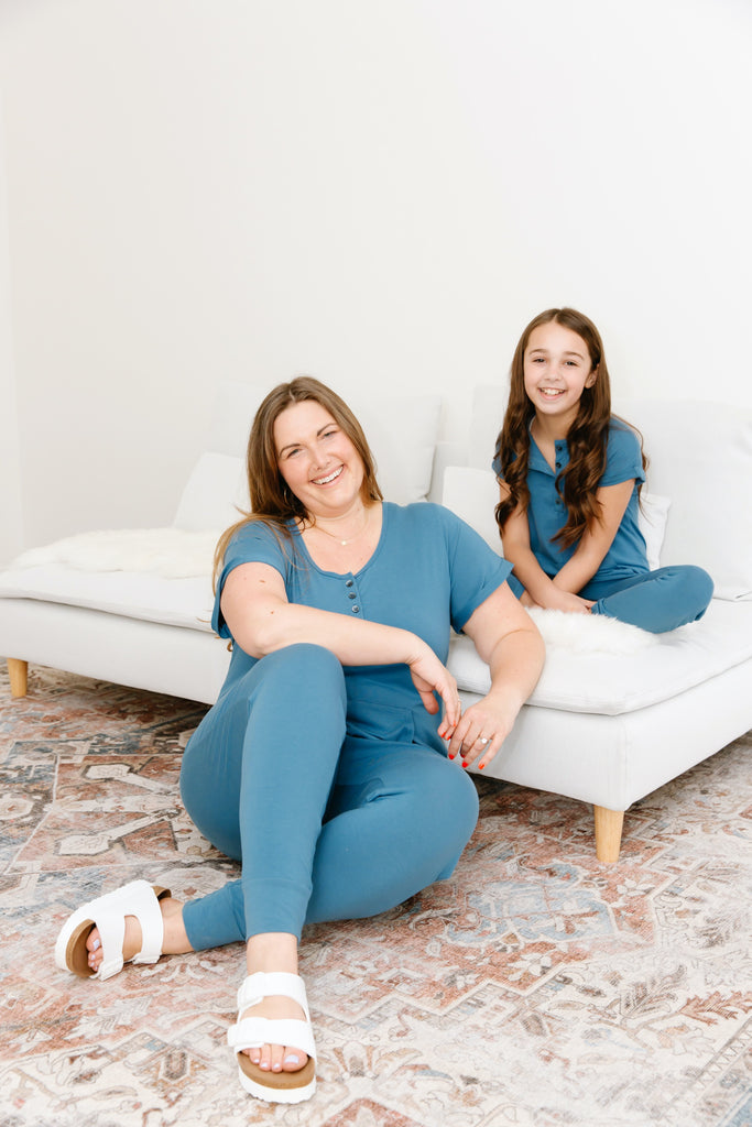 lady and child wearing matching blue smash + tess rompers sat on couch