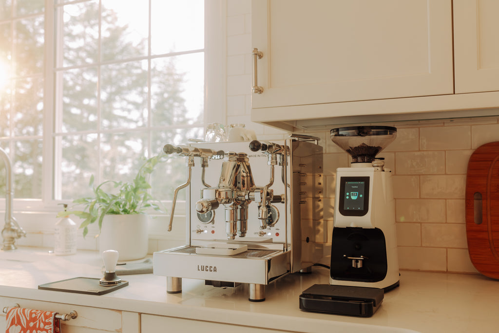 LUCCA M58 espresso machine (stainless steel) with a white LUCCA Atom 75 espresso grinder lifestyle photo by Clive Coffee