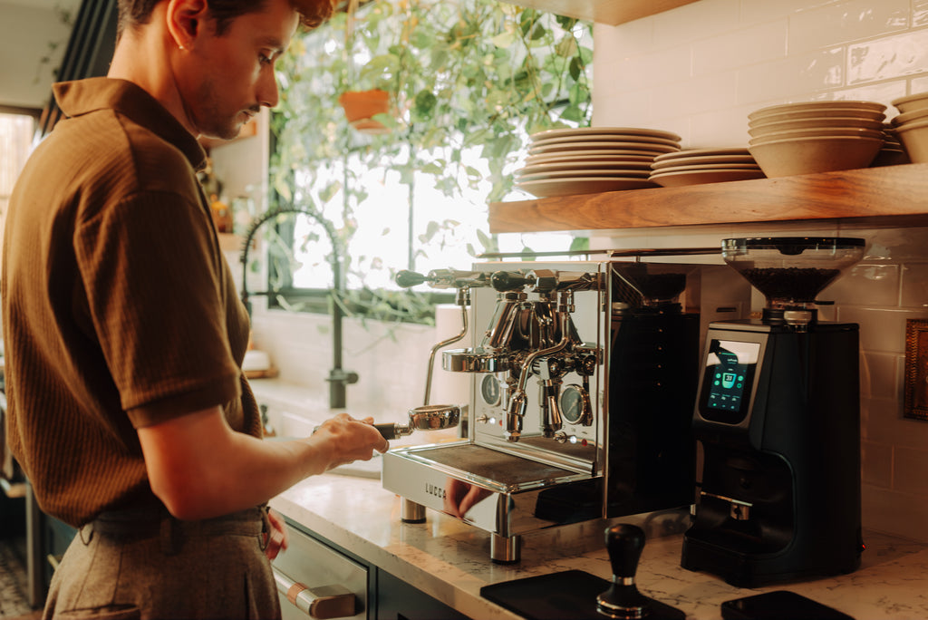 barista brewing espresso on a LUCCA M58 espresso machine with a LUCCA Atom 75 espresso grinder lifestyle by clive coffee