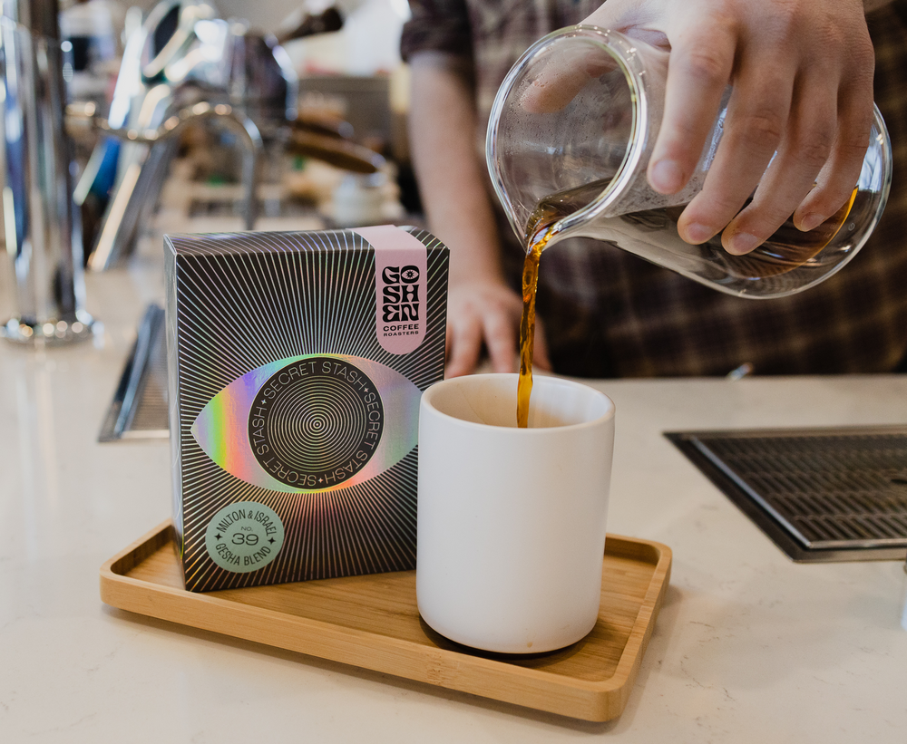 person pouring coffee into a mug next to a goshen coffee back lifestyle photo