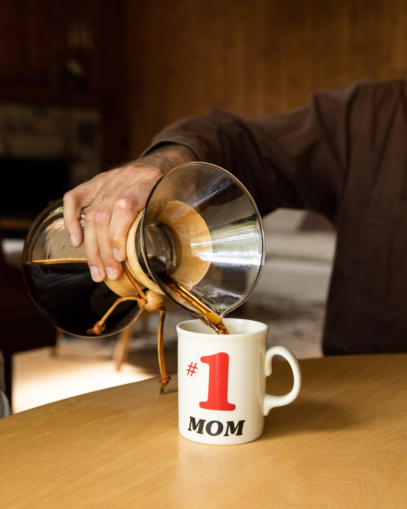 hand pouring coffee into a mug that says #1 mom lifestyle photo by clive coffee