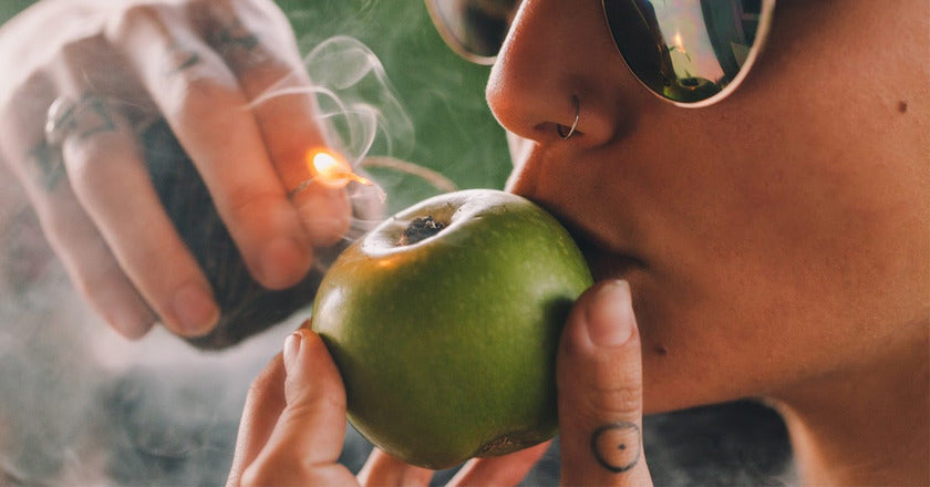 Person smoking weed using an apple pipe