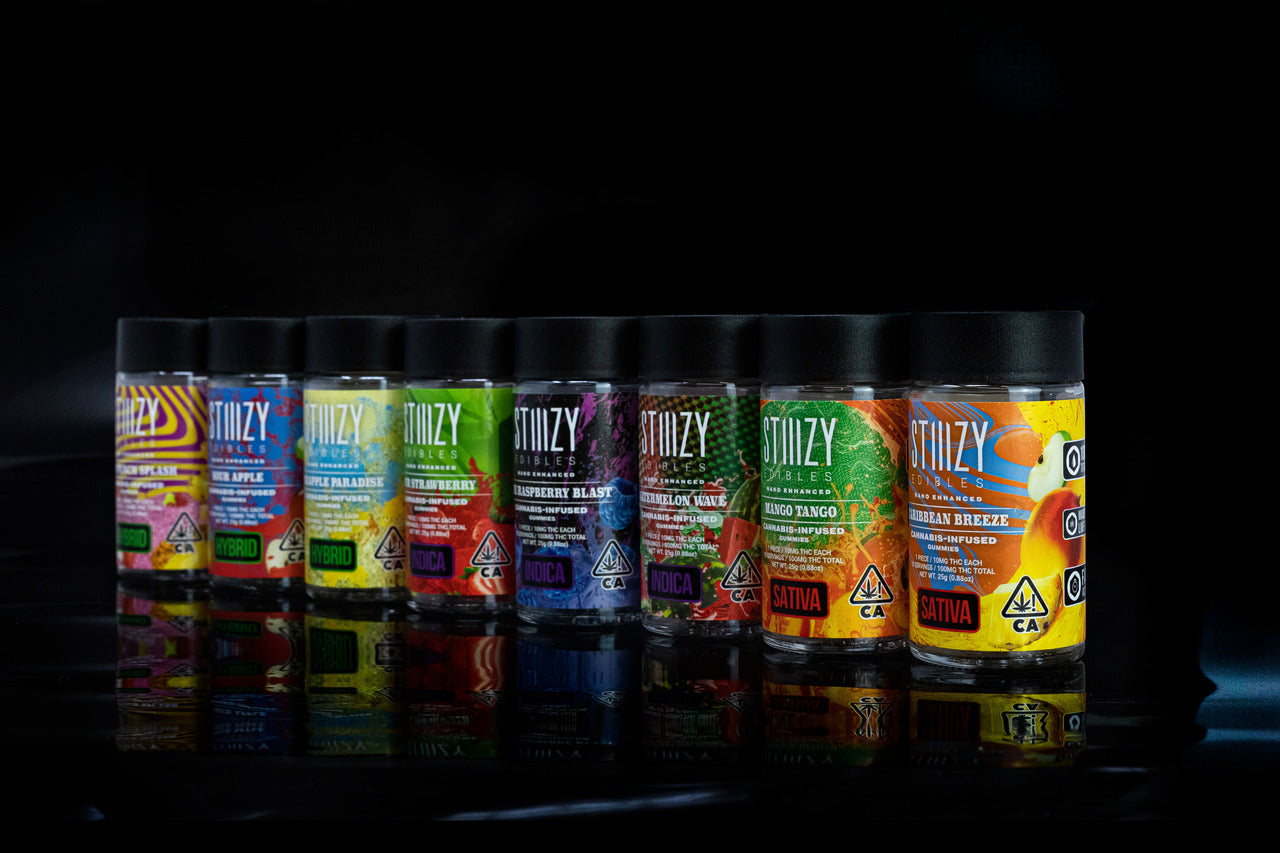 Weed gummies from sativa, indica, and hybrid strains of cannabis flower in a row of colorful STIIIZY jars.